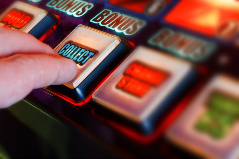 A hand on a slot machine button