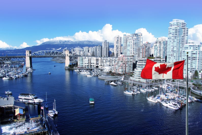 Canadian flag in front of view of False Creek and the Burrard street bridge in Vancouver, Canada