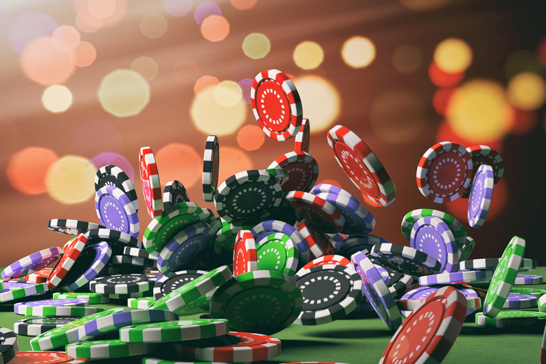 Casino poker chips falling on green felt background