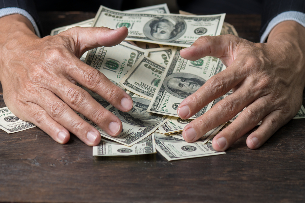 hands grabbing hundred dollar notes