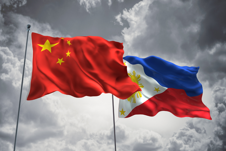 China and Philippines flags waving in the sky against dark clouds.