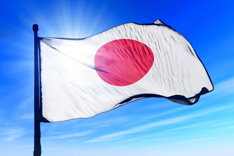Japan flag waving against clear blue sky.