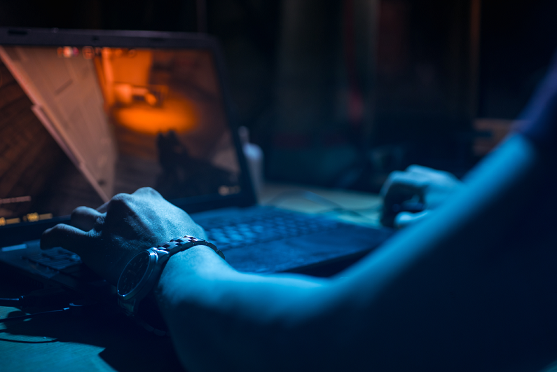 Male playing computer game in a dark room.