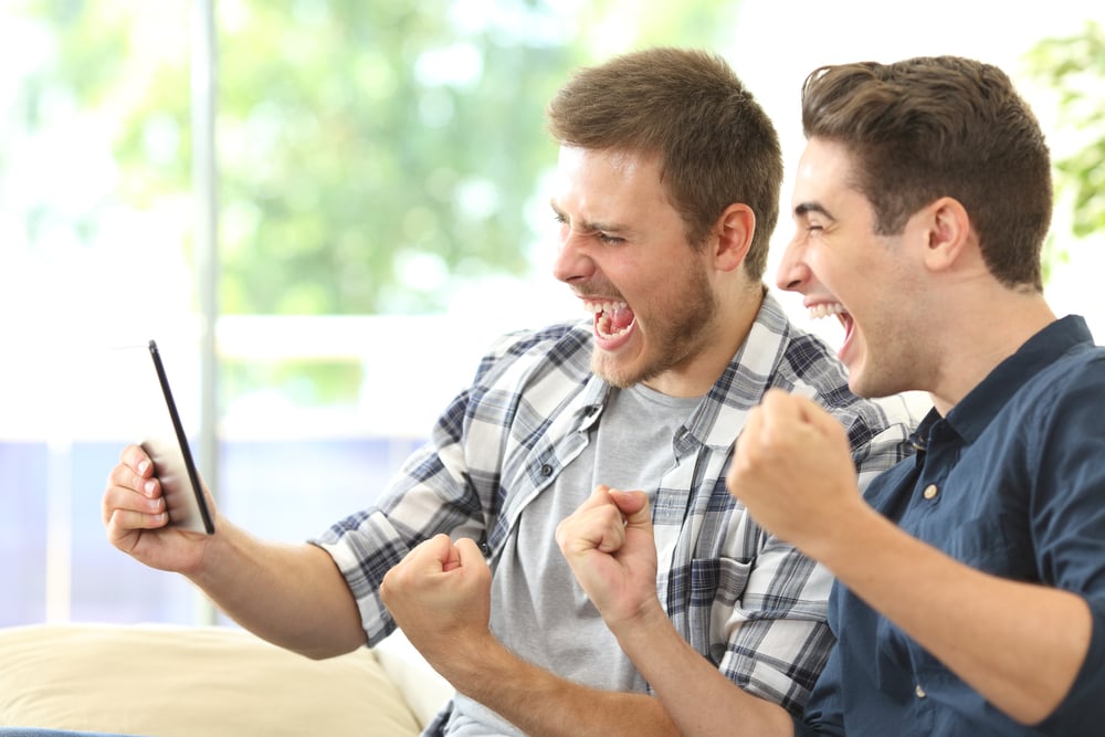 two friends watch mobile screen in excitement