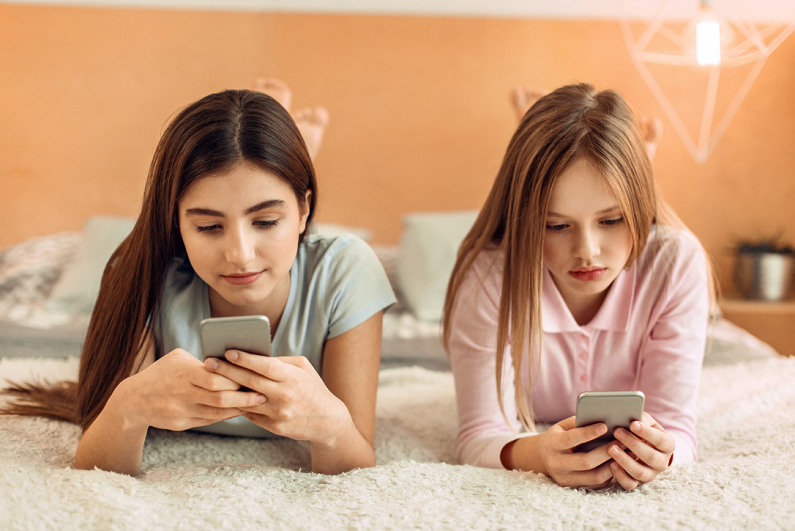 teenage-girls-using-smartphones-on-bed