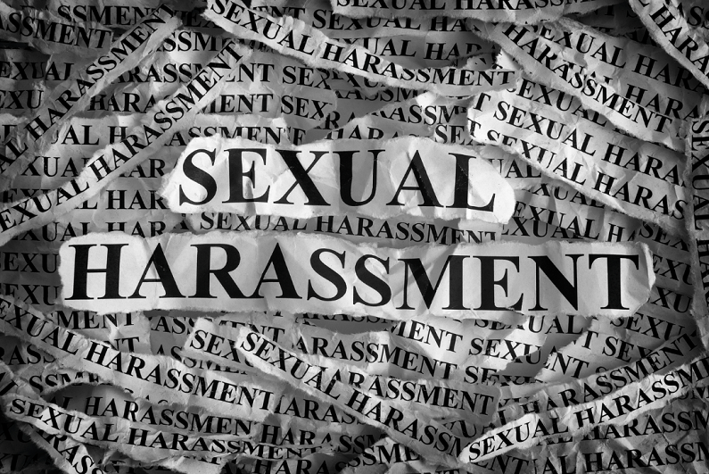 Torn pieces of paper with the words sexual harassment.