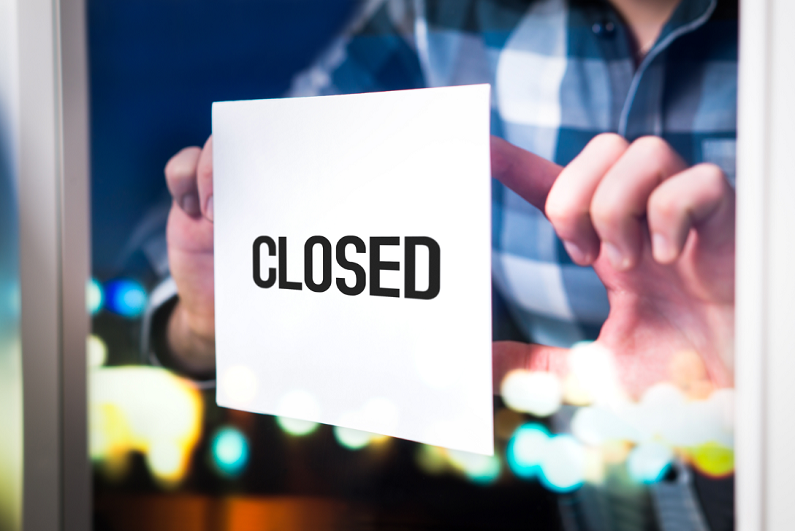 Man putting closed sign on window.