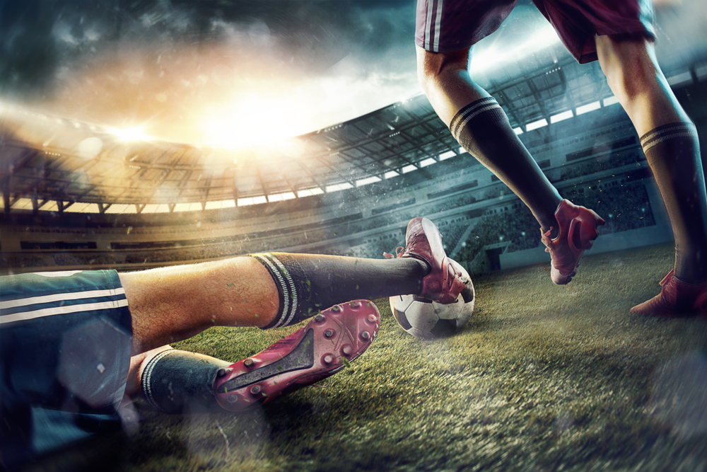 players' legs hitting a ball inside a soccer pitch