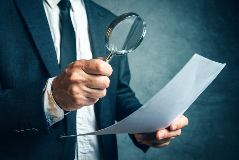 investigator looking at a piece of paper through a magnifying glass