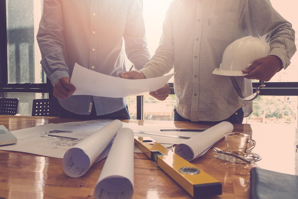 architects at work with plans and level tool on office desk