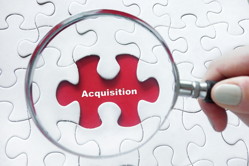 magnifying glass over jigsaw puzzle focusing on the word 'acquisition'