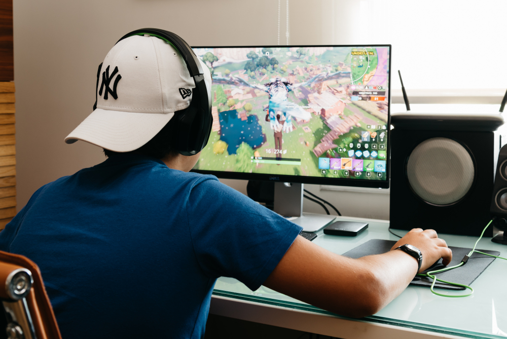 teenage boy playing Fortnite video game on his desktop computer