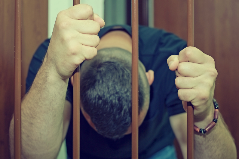 man in handcuffs behind bars