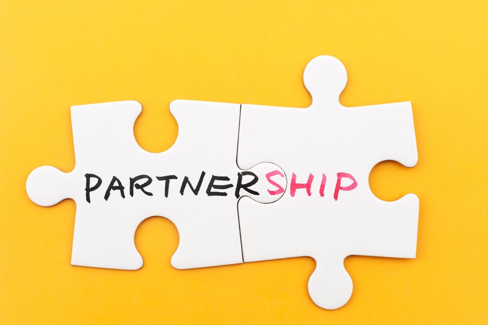 two puzzle pieces spelling out the word partnership