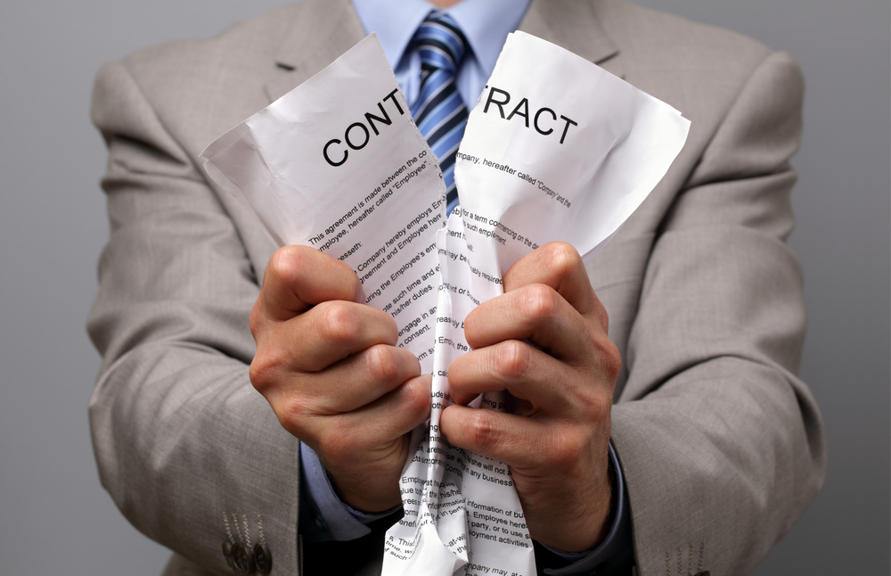 businessman in suit holding ripped contract document