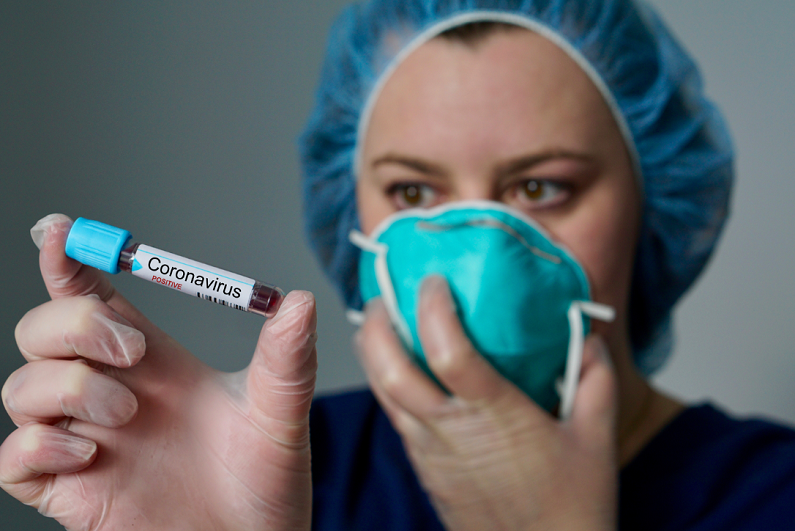 nurse wearing respirator mask holding a positive blood test