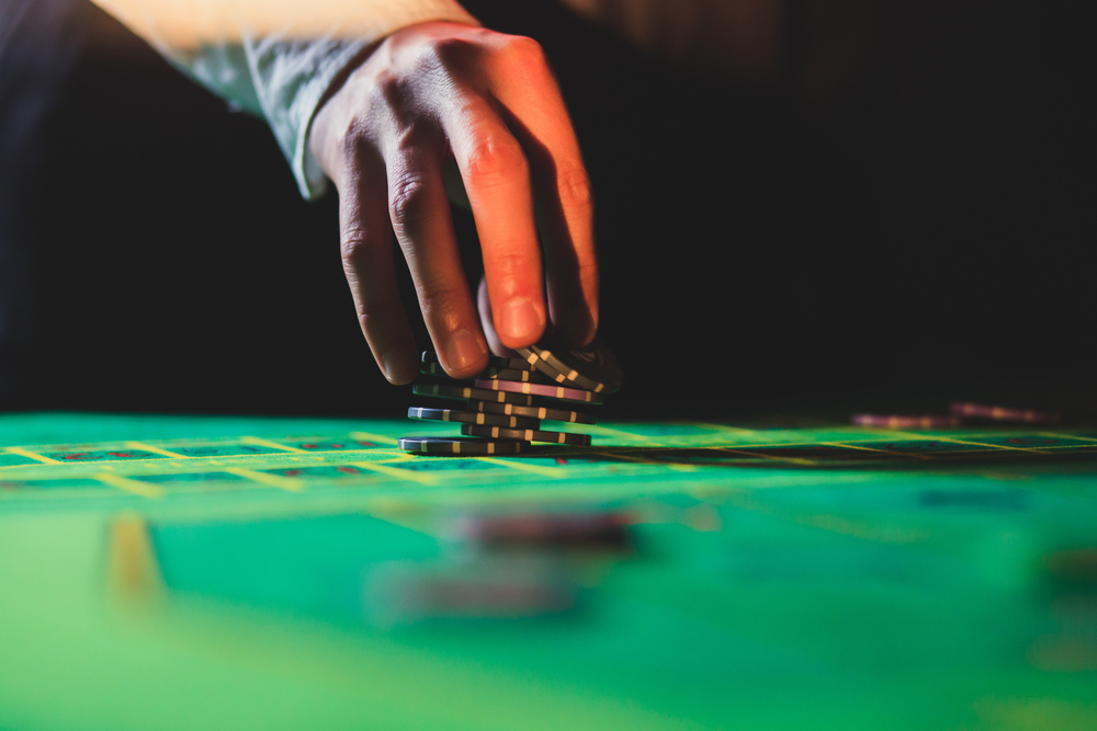 hand holding casino chips on game table
