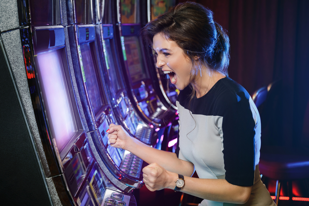 woman expresses happiness and excitement while playing at a slot machine