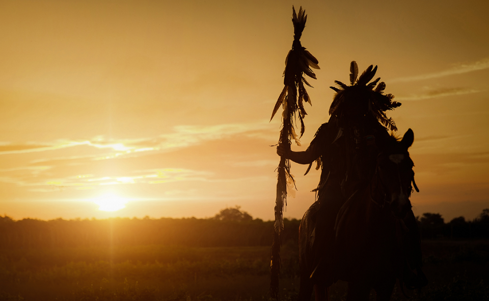 Native Indian standing against sunset