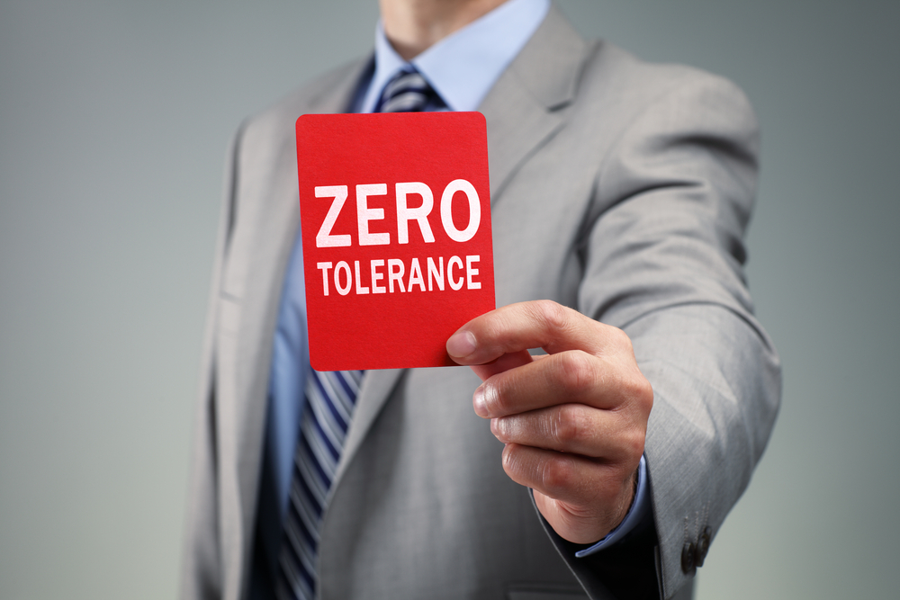 main in suit holding up zero tolerance card