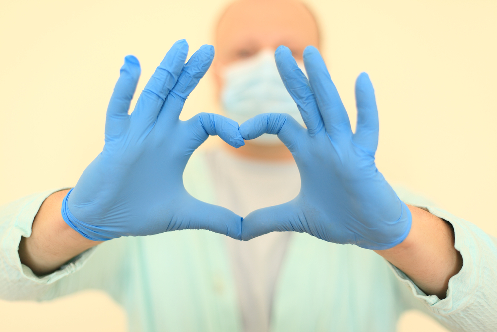 Doctor in mask and gloves makes "heart" gesture with hands