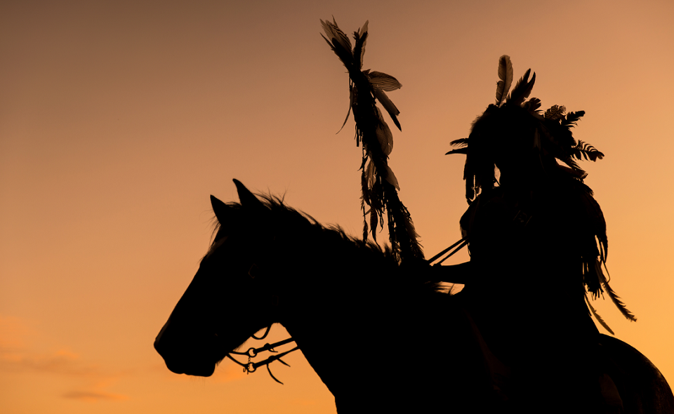native indian riding a horse in the sun
