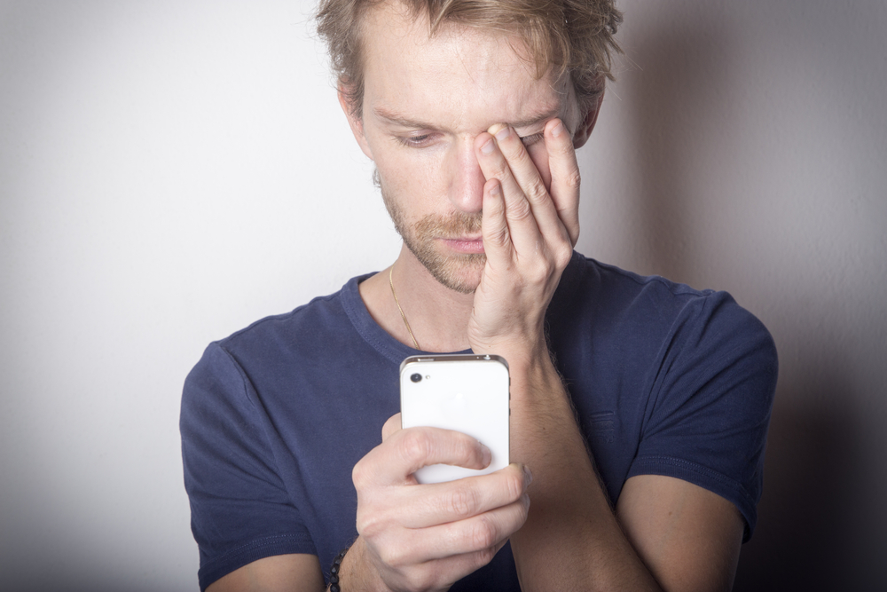 man holding smartphone and appearing upset