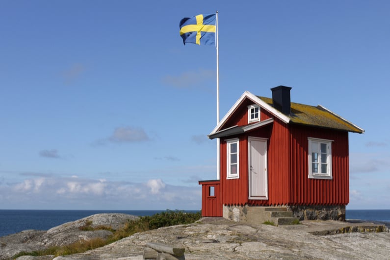 Swedish flag flying over small shack next to the water