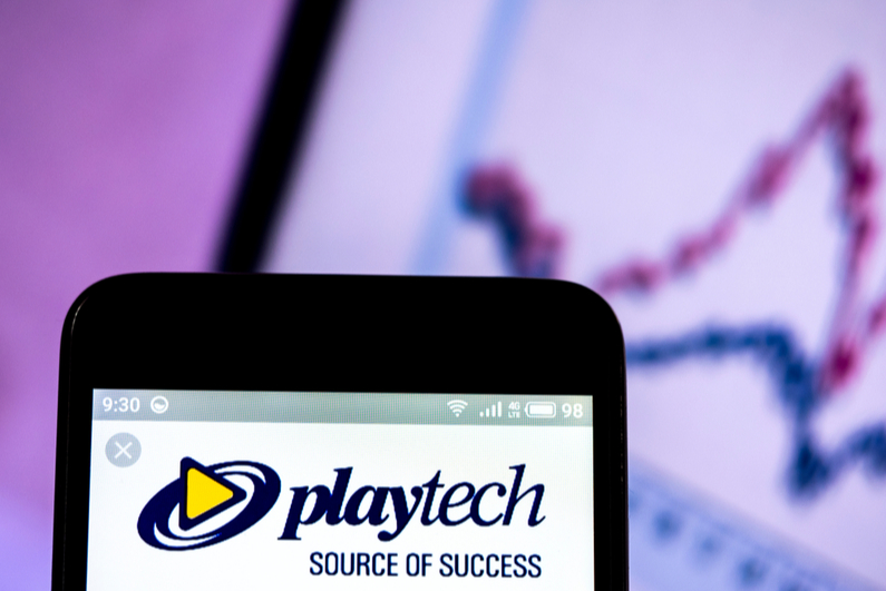 Playtech logo on smartphone with stock chart in background