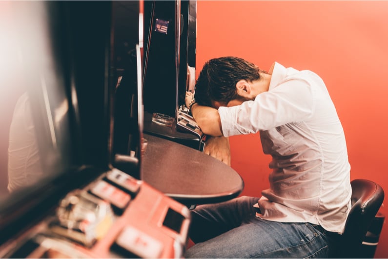 Man sad after losing money at electronic gambling machine