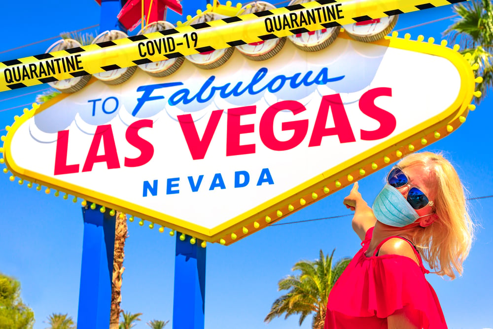 woman wearing face mask under las vegas welcome sign