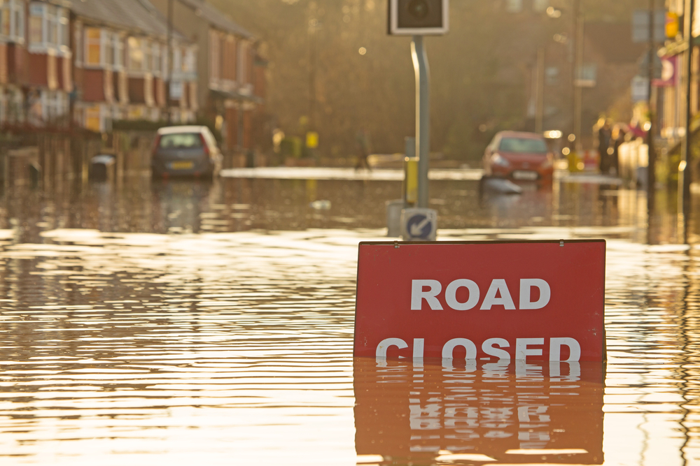 road closed sign partially submerged under flood water