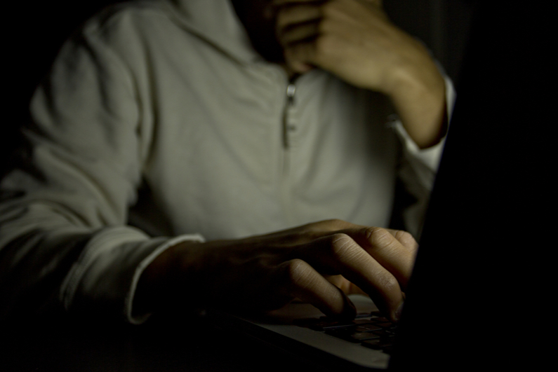 Anonymous man using laptop in a dark room