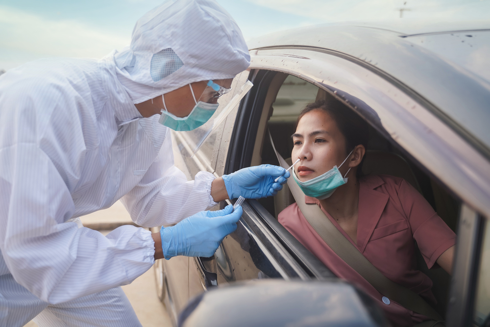 medical professional swabbing patient in car for coronavirus