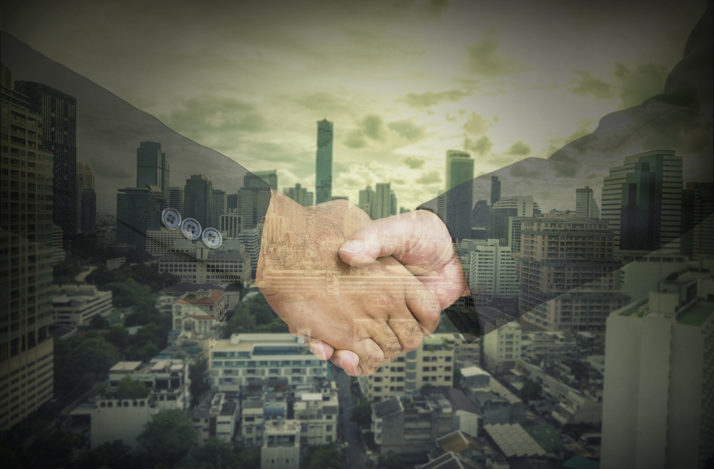 two businessmen shaking hands against a city backdrop