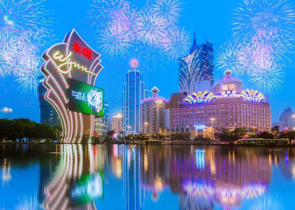 Illuminated Macau casinos stand against a fireworks-lit evening sky