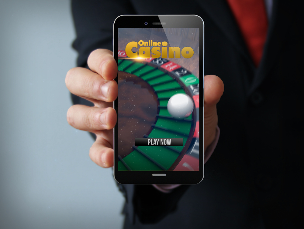 man in suit holding smartphone displaying online casino app