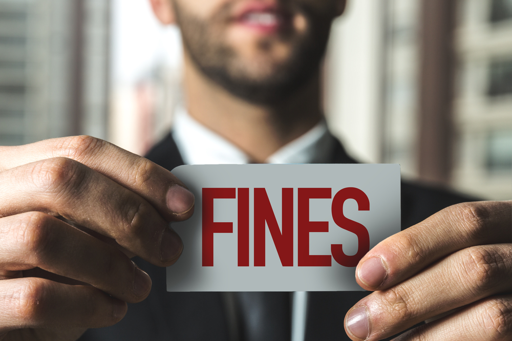 man in suit holding up card reading "fines"