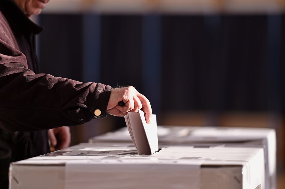 hand placing vote in ballot box