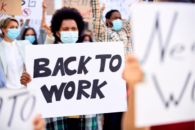 Woman wearing a mask holding a "Back to Work" sign at a rally