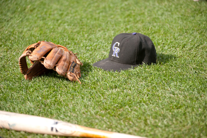 Colorado Rockies baseball cap and bat on the grass