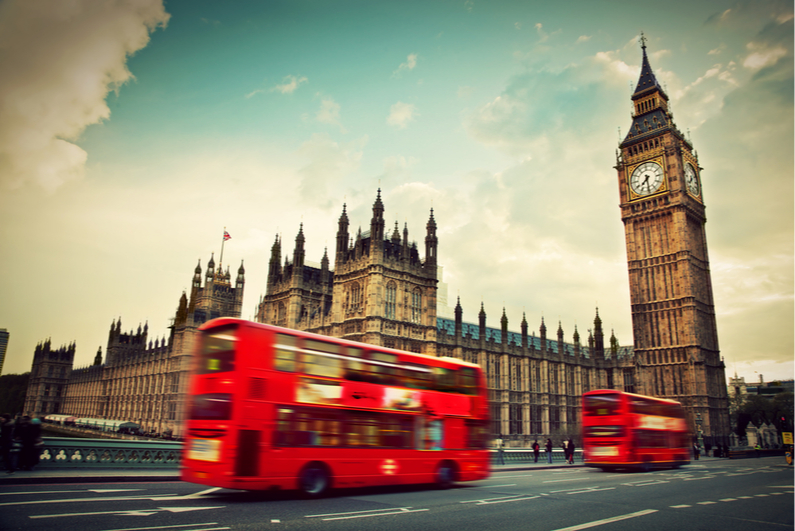 Red double-decker buses driving past Big Ben in London