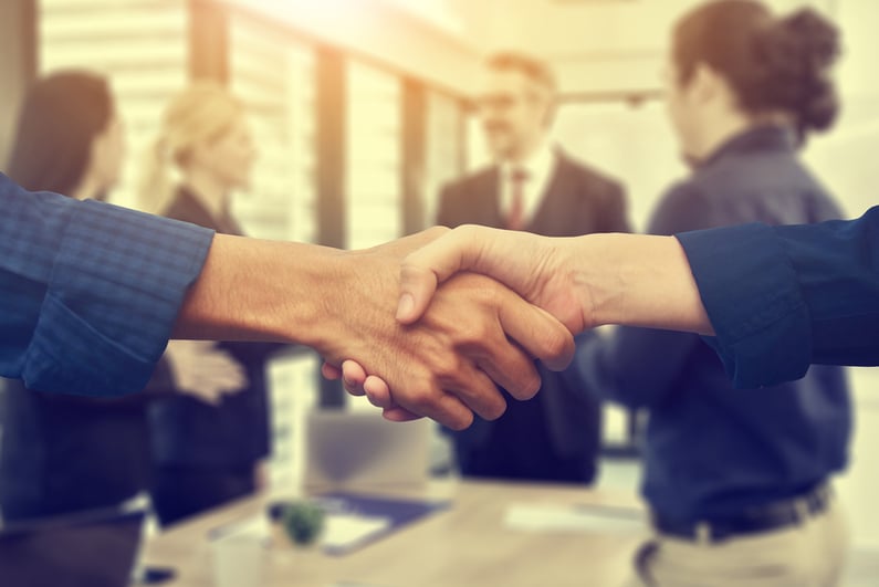 Two people shaking hands in a meeting