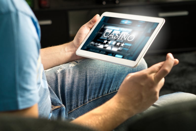 Man crossing his fingers while playing online casino games on a tablet