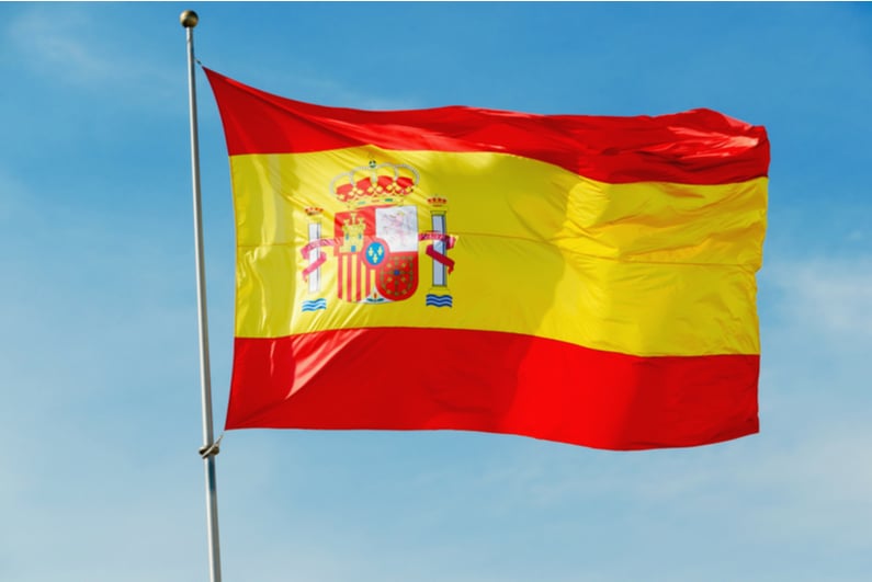 Spain's flag flying against a blue sky background