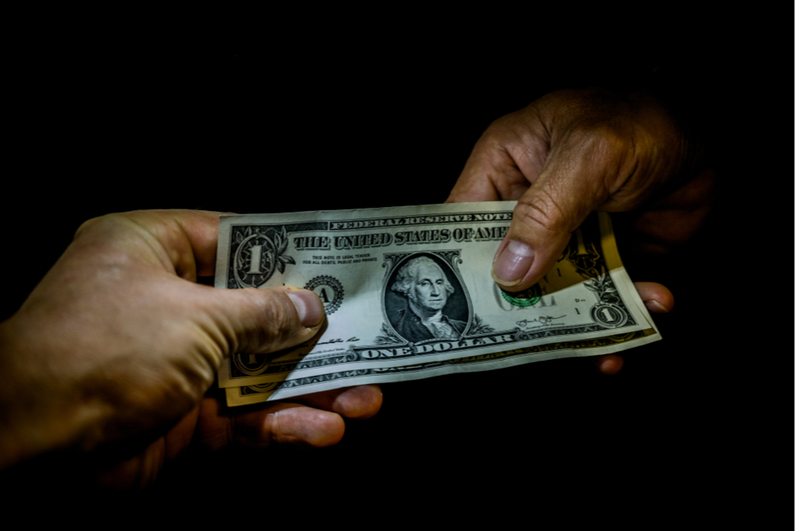 Hands exchanging money in darkness