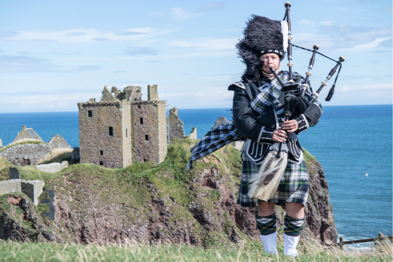 Bagpiper outside Dunnottar Castle in Stonehaven, Scotland