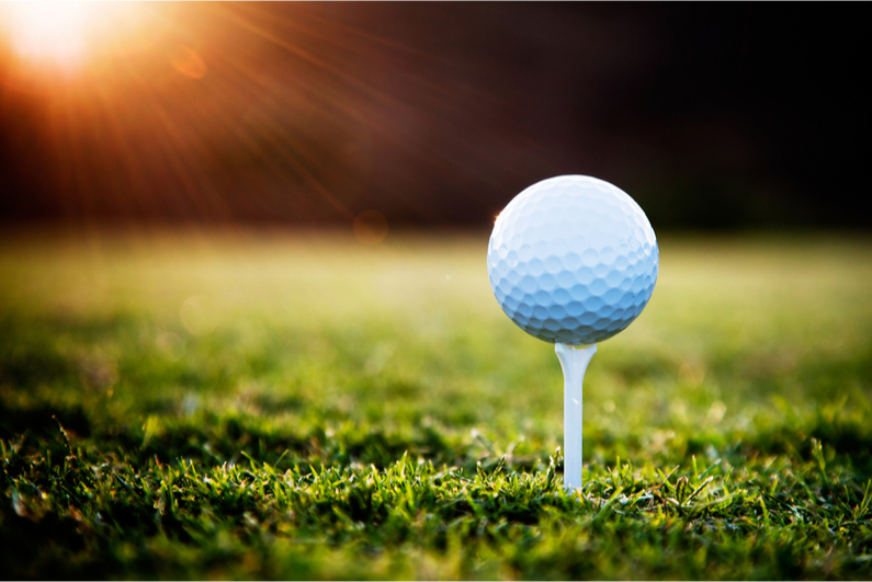 Closeup of a golf ball on a tee at sunset