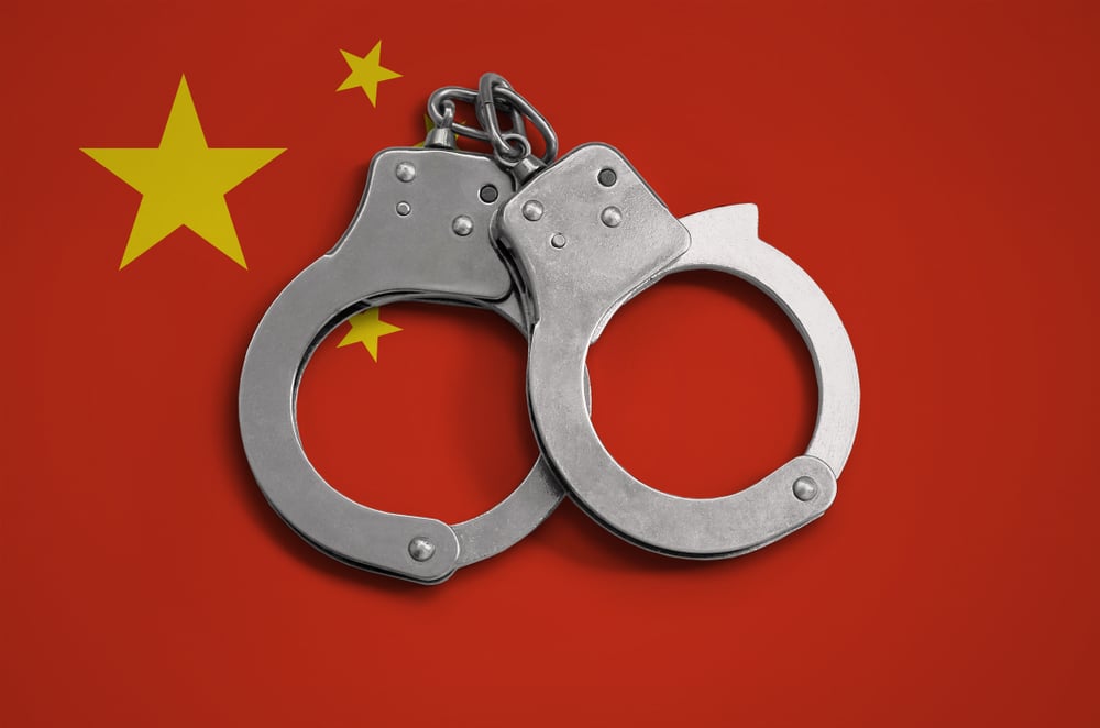 handcuffs against a China flag backdrop