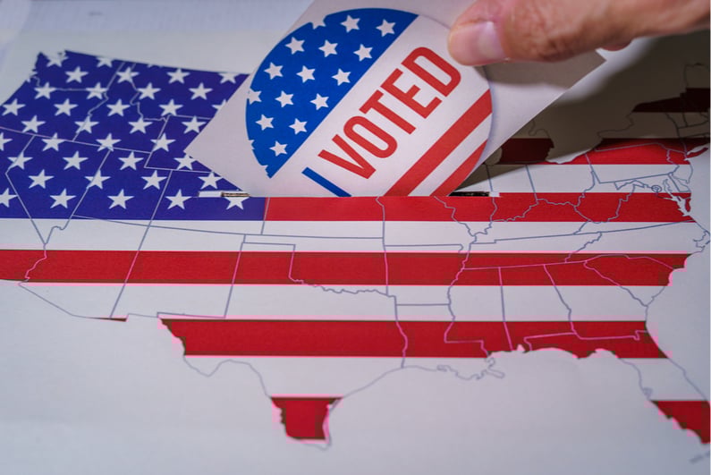 Person dropping a ballot into a ballot box with the map of the United States painted on it
